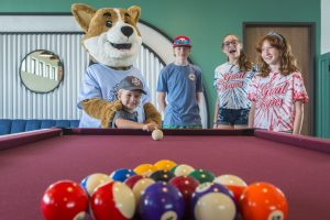 kids playing a game of pool with Biscuit the camp mascot at Great Escapes RV Resorts Bryan College Station